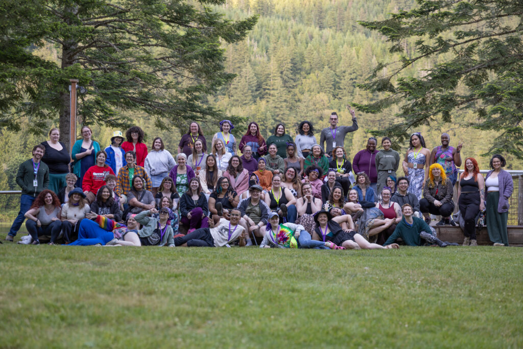 Group photo of attendees of 2026 Wombat Summer Camp in front of the lake.