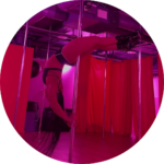 Ebony doing a crescent moon on the pole in dark pink lighting.