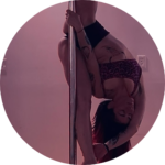 Grace doing a splitty pole move in dark lighting.