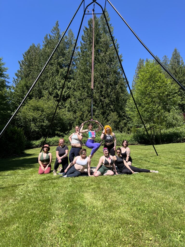 A group of people smiling in the sun posing around a Lyra.