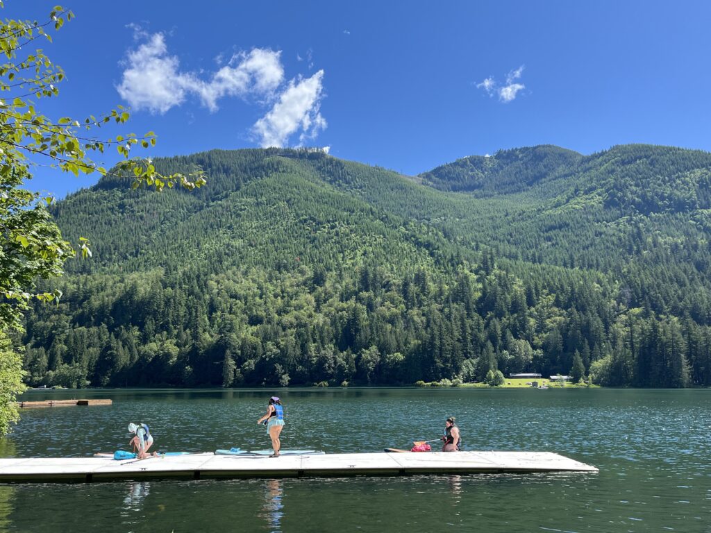 A group of 3 paddle boarders by the lake in the sun.