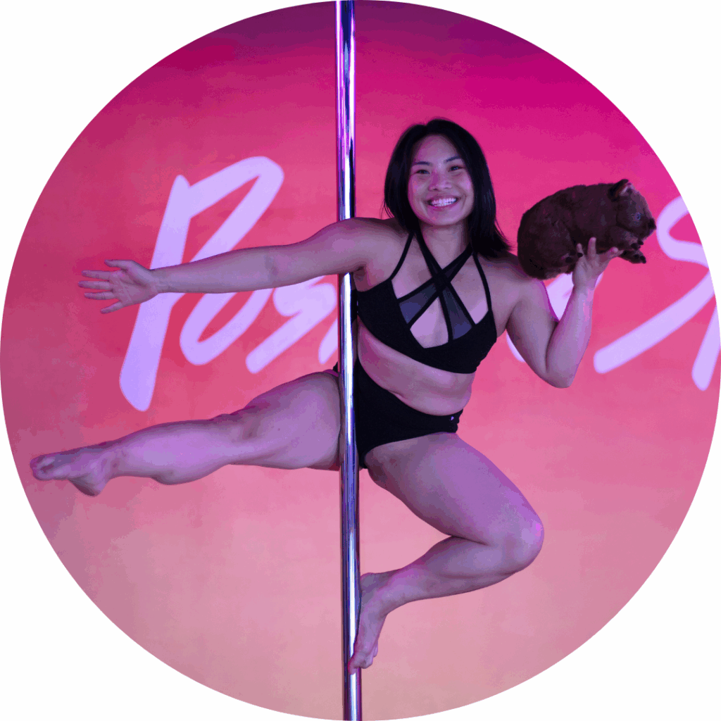 A photo of Joey doing a sit on the pole with a stuffed wombat in her hand.