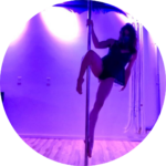 Nemi in purple lighting doing a supported 7 on the pole.