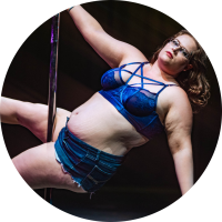 A picture of Zoe doing a scissor sit on the pole in a blue outfit.